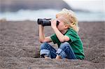 Boy using binoculars on beach