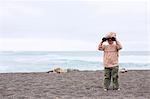 Toddler girl using binoculars on beach