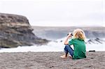 Boy using binoculars on beach