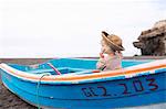 Toddler girl sitting in boat on beach