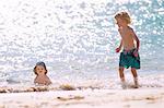 Children playing in waves on beach