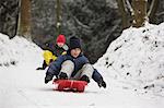 Children sledding on snowy slope