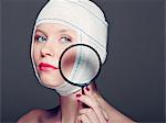 Woman in bandages with magnifying glass