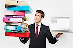 Businessman with stacks of folders and laptop