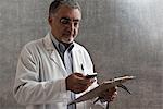 Male doctor with cellphone and clipboard