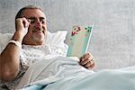 Male hospital patient  looking at get well soon card