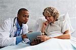 Doctor showing digital tablet to patient in hospital