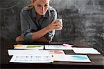 Woman looking at papers with cup of coffee