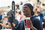 Man at sports game with foam hand and soft drink cup