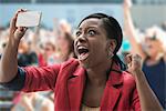 Woman in stadium, recording event with her phone