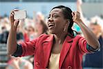 Woman in stadium, recording event with her phone