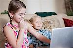 Children using laptop together on sofa