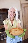 Older woman holding pie in kitchen