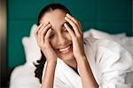Woman in bathrobe smiling on bed