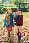 Girls playing with witch's hat and broom outdoors