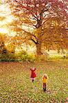 Girls playing in field of autumn leaves