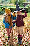 Girls playing with witch's hat and broom outdoors
