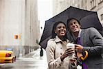 Business people holding umbrella on city street