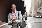 Businesswoman holding umbrella on city street