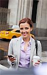 Businesswoman using cell phone on city street