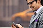 Businessman using tablet computer on city street