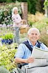 Older man in wheelchair reading newspaper outdoors