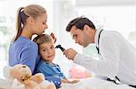 Doctor examining boy's ear at house call