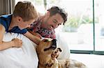 Father and son petting dog on sofa