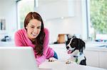 Woman using laptop with dog