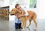 Smiling girl hugging dog in kitchen