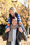 Man carrying son on shoulders in park