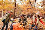 Family playing in autumn leaves in park