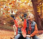 Older couple playing with grandson in autumn leaves