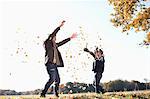 Father and son playing in autumn leaves