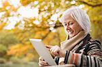 Older woman using tablet computer in park