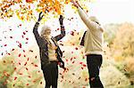 Older couple playing in autumn leaves