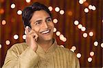 Man talking on a mobile phone in front of Diwali decoration