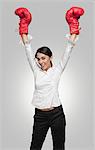 Businesswoman in boxing gloves cheering with arms raised