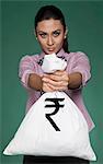 Businesswoman showing a money bag with Indian rupee symbol on it