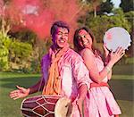 Couple celebrating Holi with musical instruments in a garden