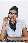 Businesswoman biting a pen and thinking