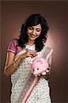 Woman putting a currency note into a piggy bank