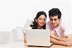 Couple sitting in a couch and using a laptop