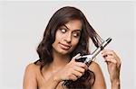 Woman using straightening irons on her hair