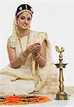 Indian woman in traditional clothing lighting an oil lamp