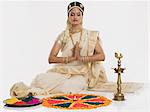 Indian woman in traditional clothing praying at Durga puja festival