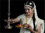 Indian woman in traditional clothing lighting an oil lamp