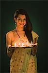 Woman holding a traditional Diwali thali and smiling