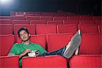Man watching movie with popcorns in a cinema hall