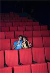 Couple enjoying soft drinks while watching movie in a cinema hall